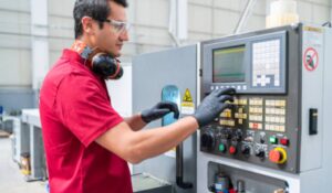 a factory worker programming a CNC cutting machine at a manufacturing factory
